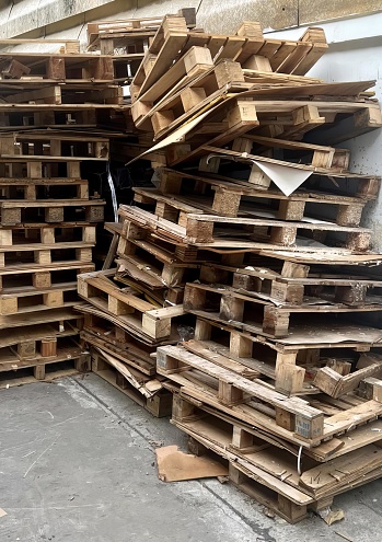 a photography of a pile of pallets sitting on the ground, lumbermill pallets stacked on the ground in a warehouse.