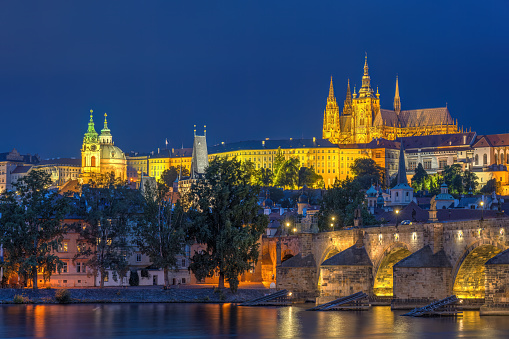 Prague (Czech Republic) with Charles bridge and St. Vitus chatedral on a Christmas evening. People walking over the bridge.