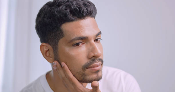 istock Handsome young man applying cream at his face while standing in front of mirror in bathroom at home. 1606756396