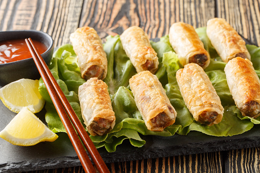 Vietnamese nem fried spring rolls with chicken and vegetables served with sauce close-up in a plate on the table. Horizontal