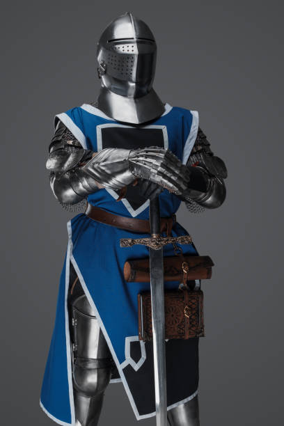 istock Medieval guard dressed in armor and blue surcoat holding a sword 1606836055