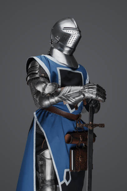 istock Medieval guard dressed in armor and blue surcoat holding a sword 1606837136