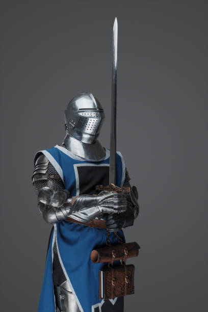 istock Medieval guard dressed in armor and blue surcoat holding a sword 1606840771
