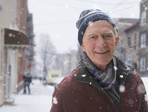 vieil homme debout sur le trottoir pendant une tempête de neige - senior adult human face male action photos et images de collection