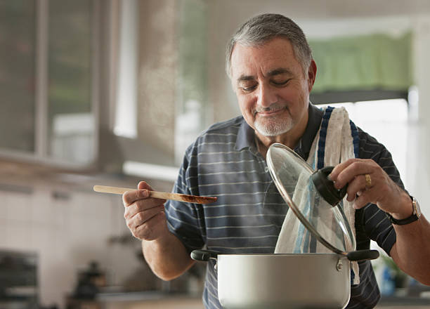 uomo anziano cucina - cucinare foto e immagini stock
