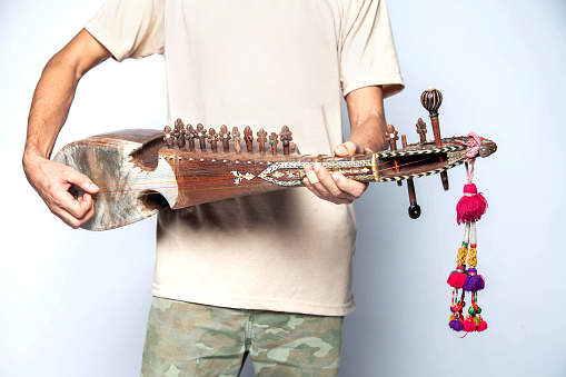 Man playing rubab a eastern folk stringed instrument of northern Pakistan isolated on white background.