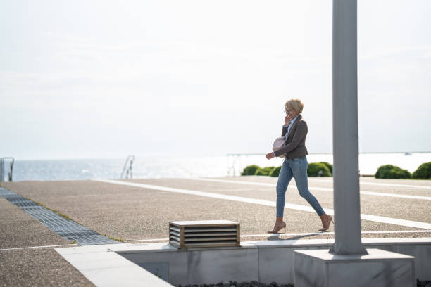 istock Woman using phone in coastal town 1606918782