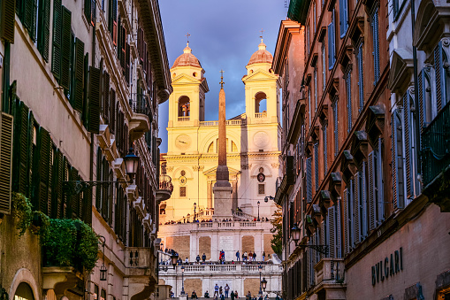 The golden hour light illuminates the splendid facade of the church of the Santissima Trinità dei Monti and the monumental staircase of Piazza di Spagna, also known as the Spanish Steps, in the historic and Baroque heart of Rome. Built starting from 1502 in the Renaissance style, this church was commissioned by Charles VIII, King of France, to give a stable accommodation to the religious Order of the Minims. In 1570 the façade was rebuilt based on a design by the architects Giacomo Della Porta and Carlo Maderno, with the construction of the two characteristic bell towers. A masterpiece of the late Roman Baroque, the monumental staircase of the Trinità dei Monti was built in 1721 to connect the church with the underlying Piazza di Spagna. Designed by the architect and urban planner Francesco De Sanctis, the Spanish Steps were inaugurated by Pope Benedict XIII on the occasion of the Jubilee of 1725. In 1980 the historic center of Rome was declared a World Heritage Site by Unesco. Image in high definition quality.