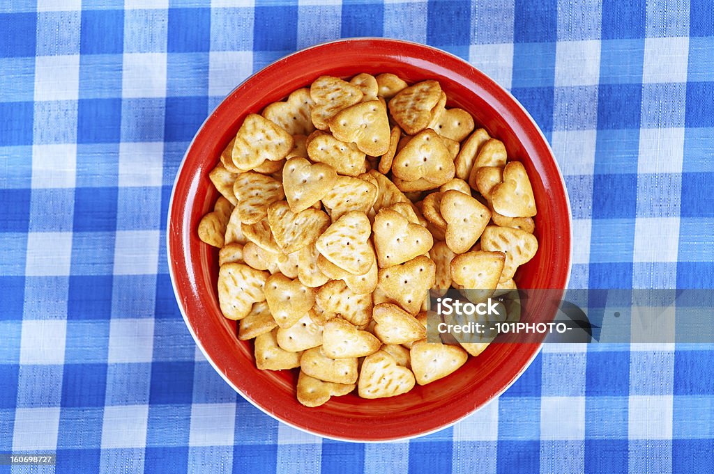 Fine biscuits in shape of heart Fine biscuits in shape of heart in red plate on blue checkered tablecloth. Baked Stock Photo