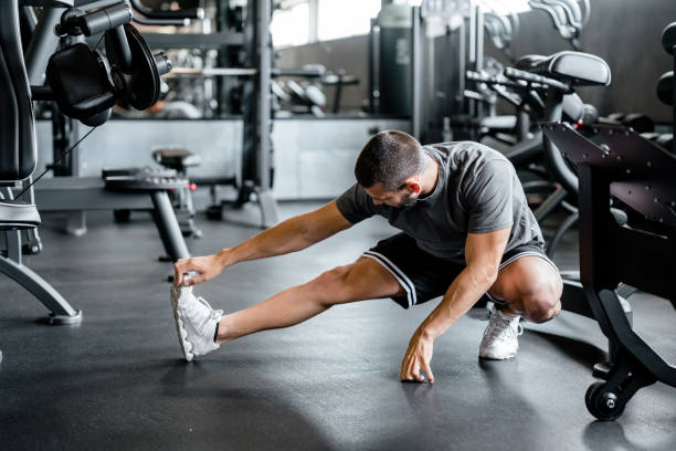 istock Young fit man doing stretching exercises in the gym 1607000559