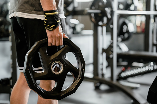 Close-up of male athlete holding weights at the gym