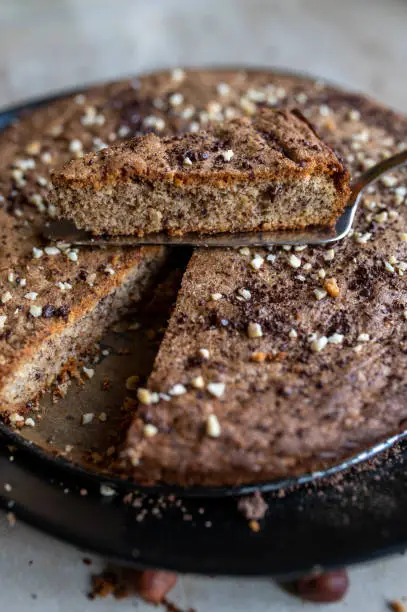 Healthy gluten free nut cake with dark choclate. Baked with almond flour. Served ready to eat with cross section view. Closeup with selective focus.