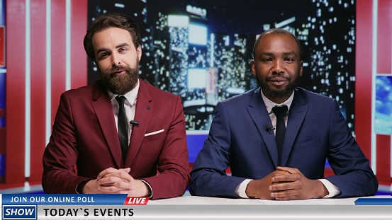 Media team starting late night talk show in newsroom, diverse journalists in suits presenting international news on live television transmission. Two presenters working as tv hosts.