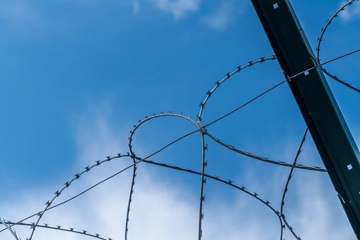 Barbed Wire on the fence, low angle view against bright blue sky