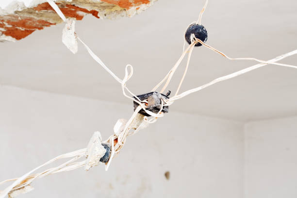 Very old power plugs and cables hanging from the ceiling. Home renovation with replacing the old eletricity wiring