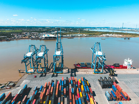 Norfolk, VA, USA -- June 6, 2019. A photo of a row of shipyard cranes set against a bright hazy sky in Port Virginia, Norfolk.