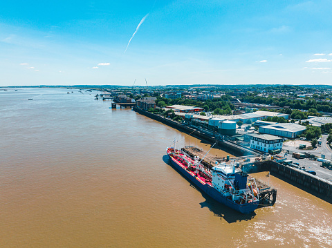 Huge green contaner ship under loading operation with blue gantry cranes in the port of Felixtowe