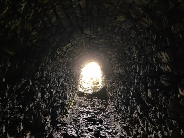 istock Light at the end of a long stone tunnel 1607108509