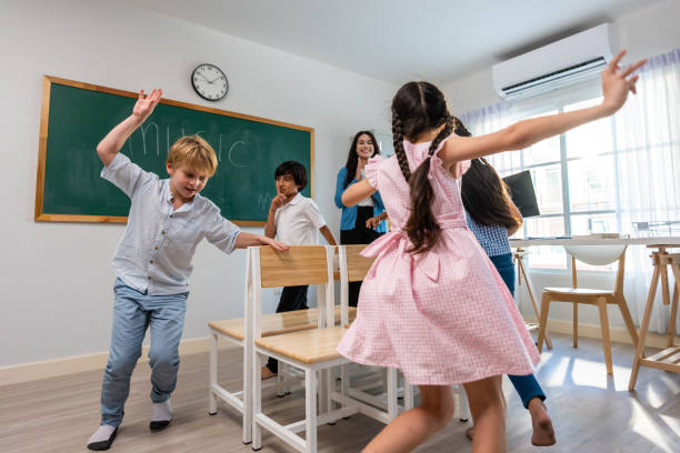Group of student learn with teacher in classroom at elementary school. Attractive beautiful female instructor master support and look after children doing fun activity with happiness at kindergarten.