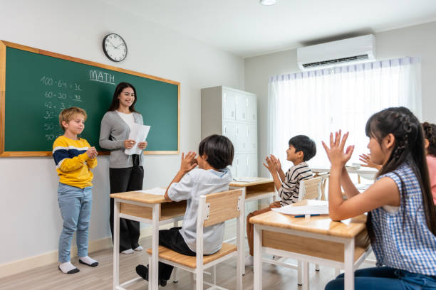 istock Group of student learn with teacher in classroom at elementary school. Attractive beautiful female instructor master explain and educate young children with happiness and fun activity at kindergarten. 1607117897