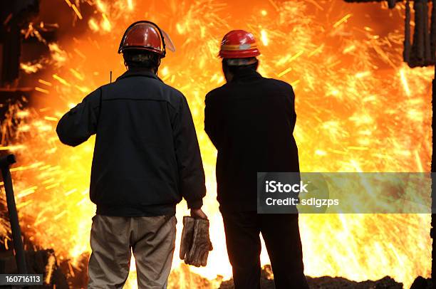 Photo libre de droit de Deux Hommes À Regarder Le Fer En Fusion Éclabousser banque d'images et plus d'images libres de droit de Acier