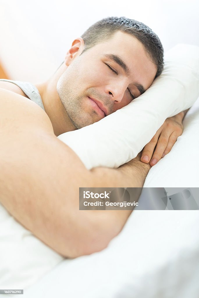 Atraente jovem dormindo em uma cama macia e de alta qualidade. - Foto de stock de Cama royalty-free