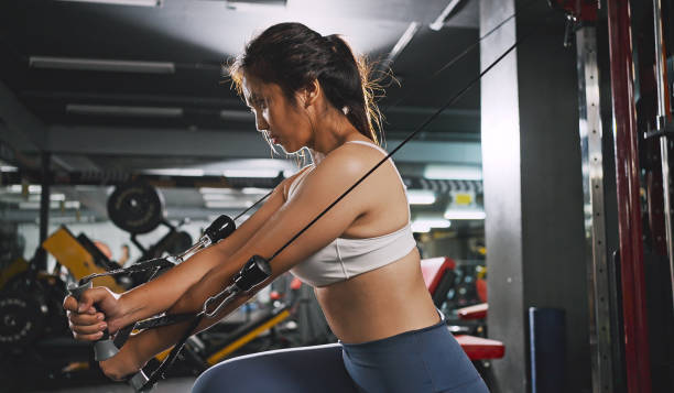 Sporty woman exercising on multistation at gym for arm and shoulders muscles. Fitness exercising in gym. Sporty woman exercising on multistation at gym for arm and shoulders muscles. Fitness exercising in gym. cable crossover ripl fitness