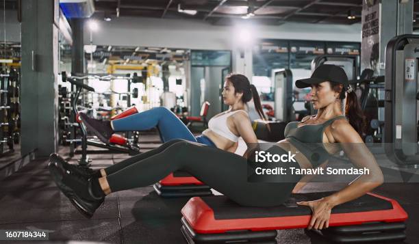 Two Young Woman Doing Knee Tuck Crunches In The Gym Powerful Female Bodybuilder Pumping Abs Muscles Stock Photo - Download Image Now