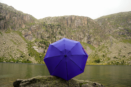 blue umbrella in the mountains with a lake. bad weather hiking