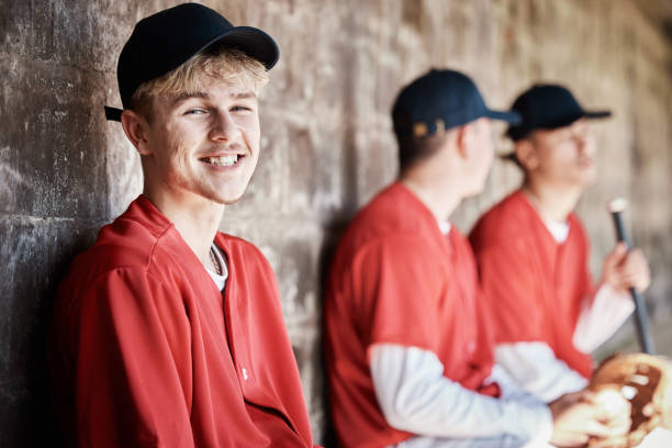 istock Baseball player portrait, bench or happy man in a game, competition or training match on a stadium pitch. Softball workout exercise, funny face or players laughing or playing a game in team dugout 1607221915