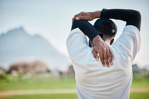 Baseball field, back view or black man stretching in training ready for match on field in summer. Workout exercise, fitness mindset or focused young sports player in warm up to start playing softball