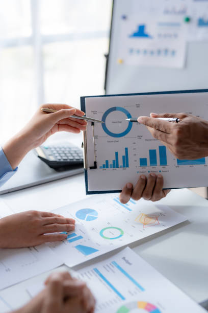 Business team together making investment plan at meeting pointing at graph and chart analyzing company financial report.