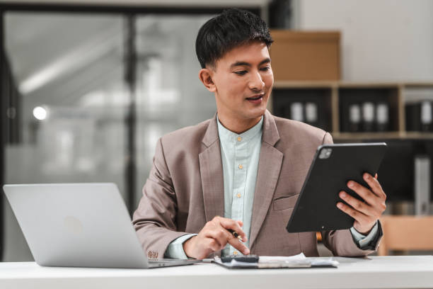 istock Using tablet pc, Asian business asian man supervisor analyse financial report of responsible worker pay attention on mistakes propose correction. 1607244302