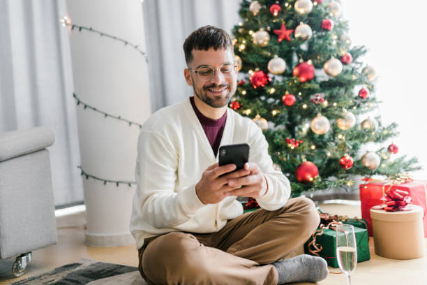 istock A man sending greetings for the new year while sitting next to the Christmas tree 1607244885