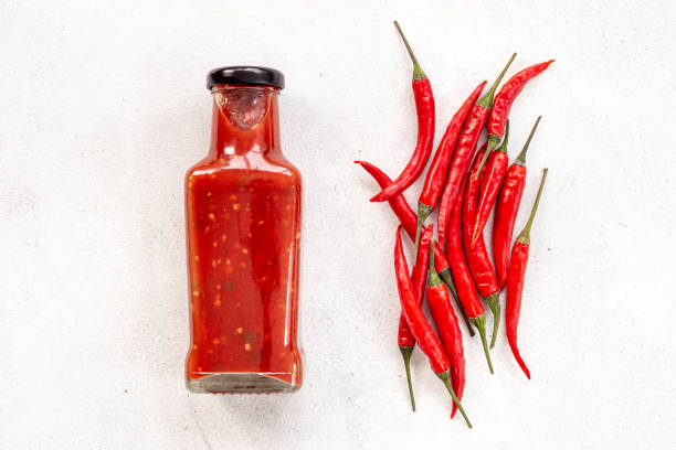 istock Red chili pepper sauce in bottle with ripe hot pepper 1607269325