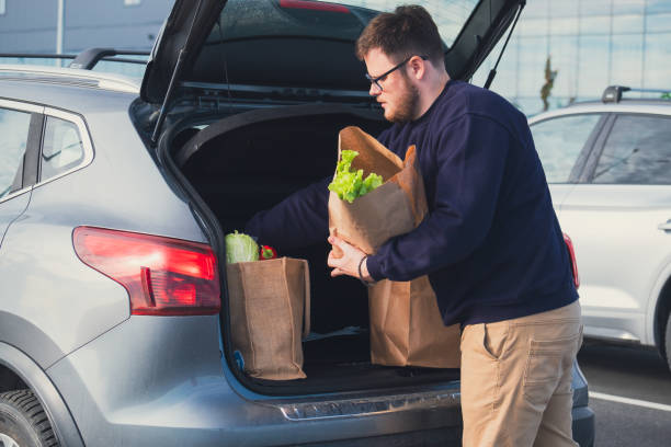 istock happy man put groceries bag in car trunk 1607316821