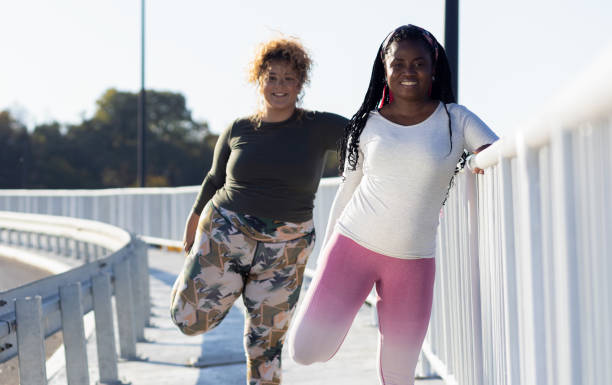 istock Two young plus size women stretching together before running. 1607319998