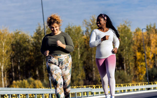 istock Two young plus size women jogging together. 1607320585