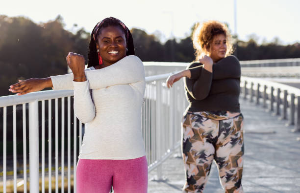istock Two young plus size women stretching together before running. 1607320642