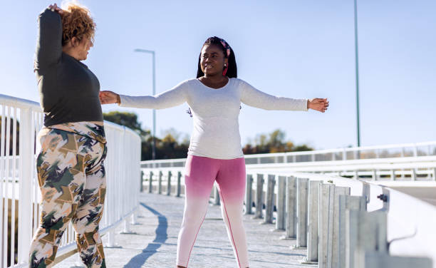 istock Two young plus size women stretching together before running. 1607321185