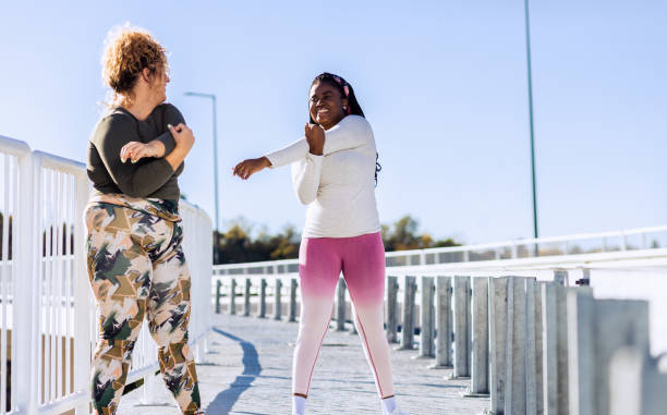 istock Two young plus size women stretching together before running. 1607321208