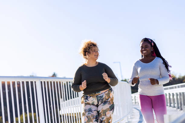 istock Two young plus size women jogging together. 1607321257