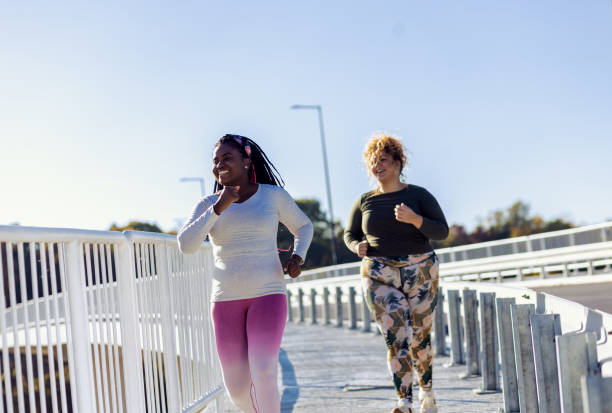 istock Two young plus size women jogging together. 1607323447