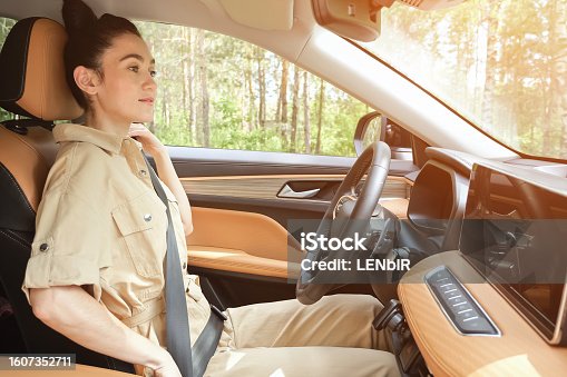 istock Black-haired woman fastens seat belt taking care of safety 1607352711