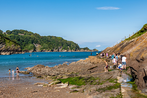 Combe Martin, UK. 10 August 2023. People walking on the raised beach footpath at Combe Martin in Devon