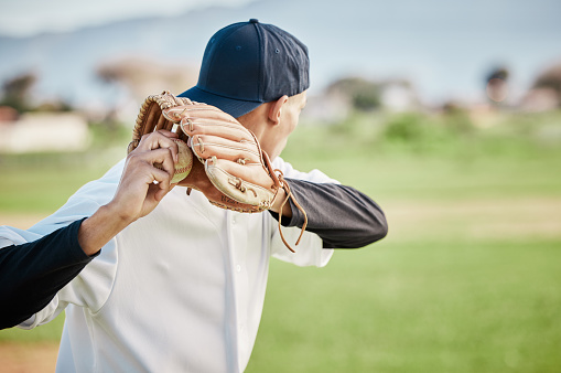 Pitcher, back view or sports man in baseball stadium in a game on training field stadium. Fitness, young softball athlete or focused man pitching or throwing a ball with glove in workout or exercise