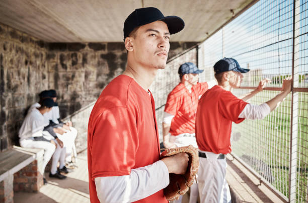 baseball, pitcher or dugout with a sports man watching his team play a game outdoor during summer for recreation. sport, teamwork and waiting with a male athlete on the bench to support his teammates - men baseball cap focus determination imagens e fotografias de stock