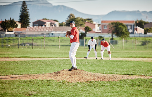 A baseball pitcher is on the mound getting ready for his next pitch. The pitcher and the field are in shadows and create a sense of solitude.