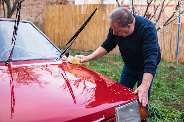istock A senior man holds a sponge and washes a car in his backyard. 1607380359