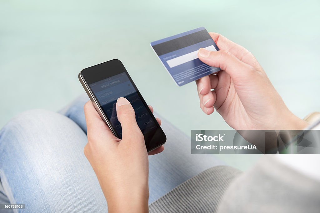 Woman using credit card to shop on smart phone Woman verifies account balance on smartphone with mobile banking application. Adult Stock Photo